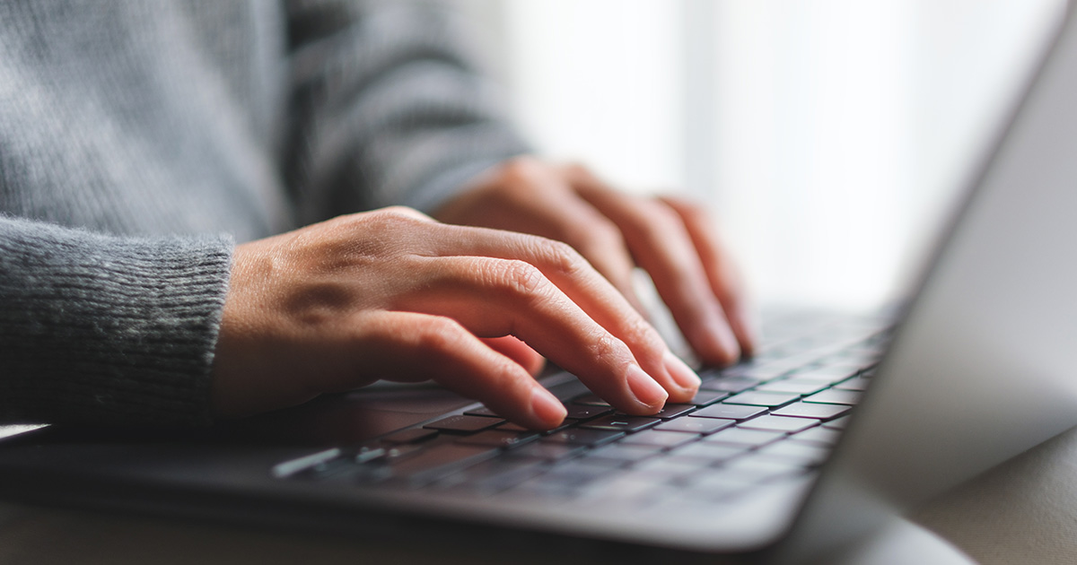 Hands typing on a laptop computer