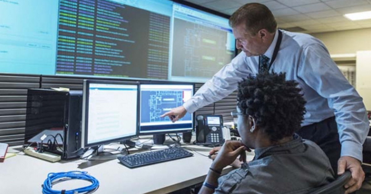 Two people examine screens with data displayed