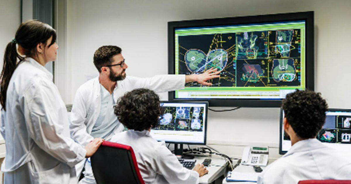 Healthcare worker pointing at medical image on a display to coworkers