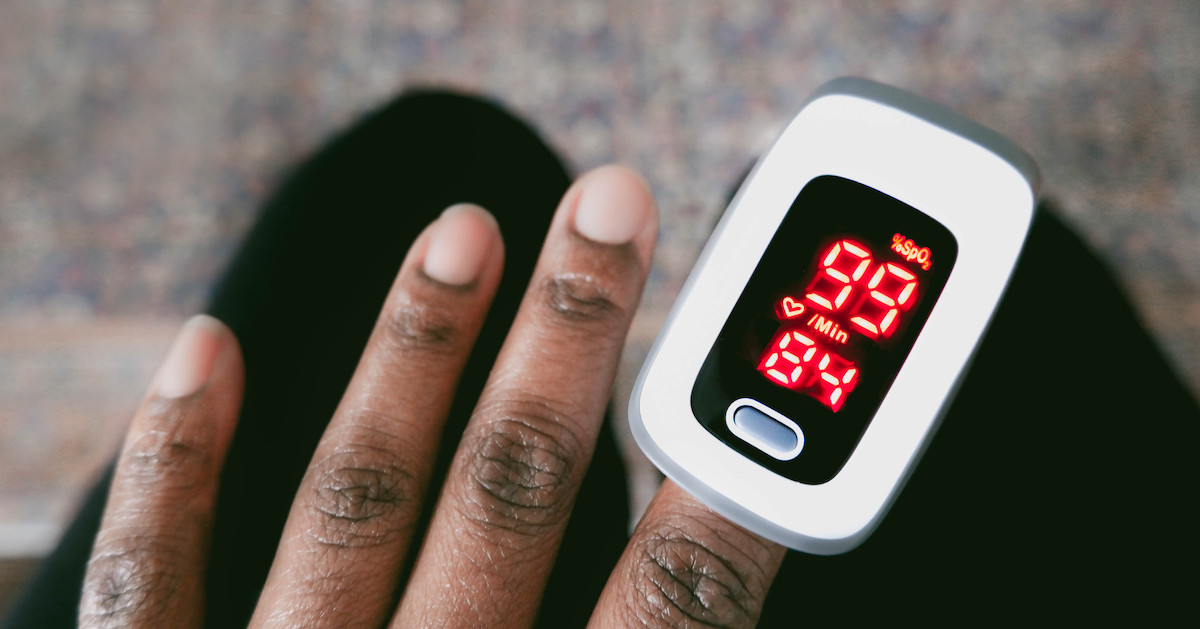Dark skinned hand with a pulse oximeter measuring the patient's oxygen levels