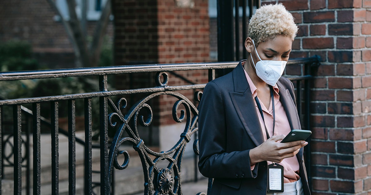 Woman in mask checks smartphone for update