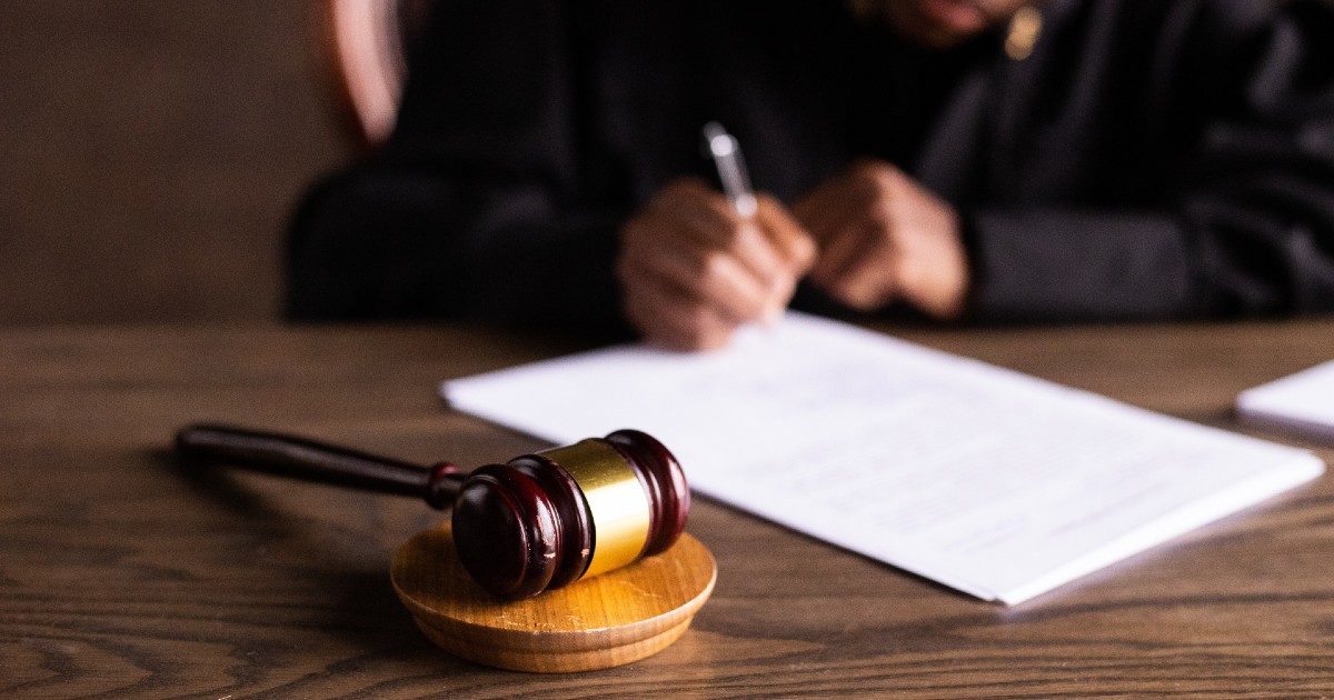 gavel on desk and judge's hands singing paper