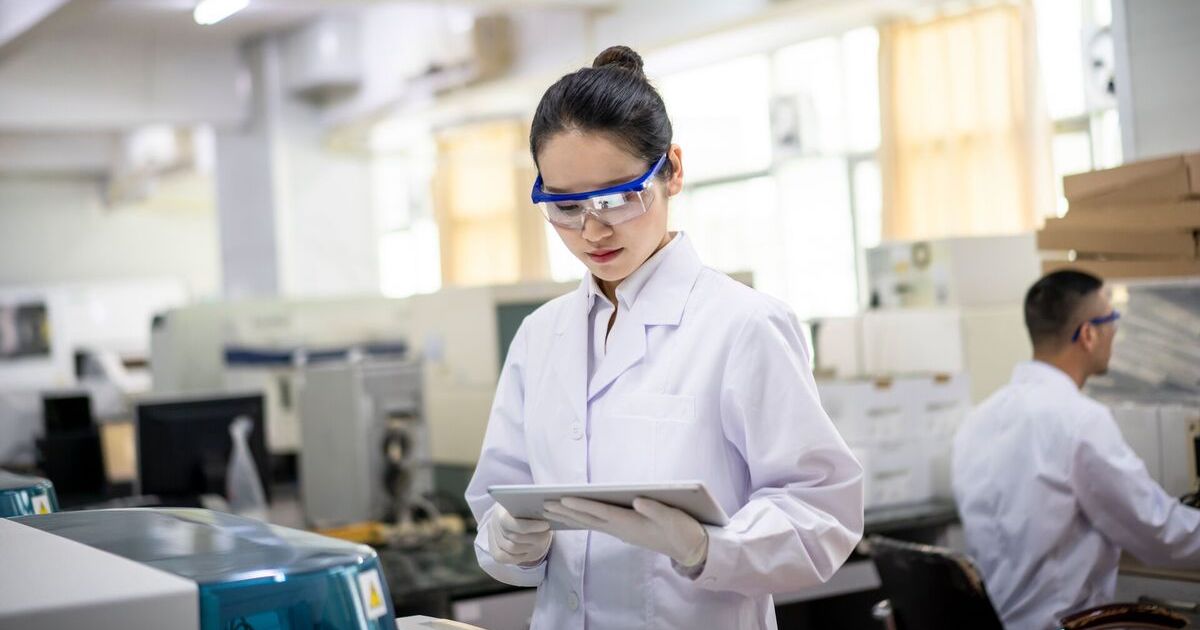 A laboratory scientist reading data from a digital tablet