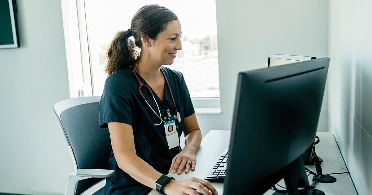 A doctor reviewing a patient's file on a desktop computer
