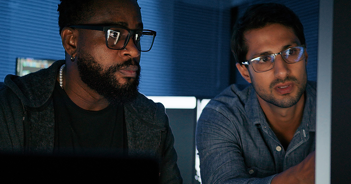 IT security staff discuss threat information in front of a network terminal 