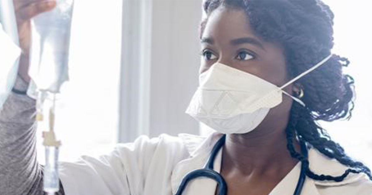 Healthcare worker in mask holding IV drip bag