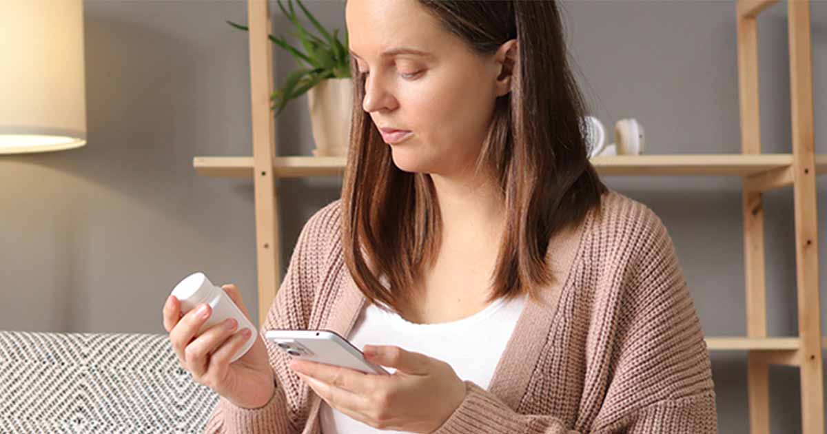 Person holding pill bottle and smart phone