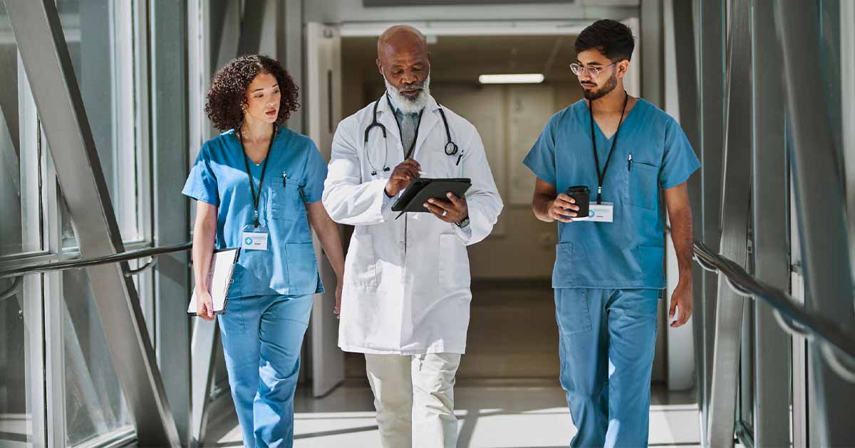 Healthcare workers walking with doctor in hospital hallway
