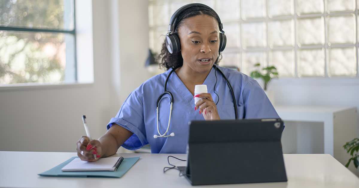 Doctor talking notes while talking to a tablet