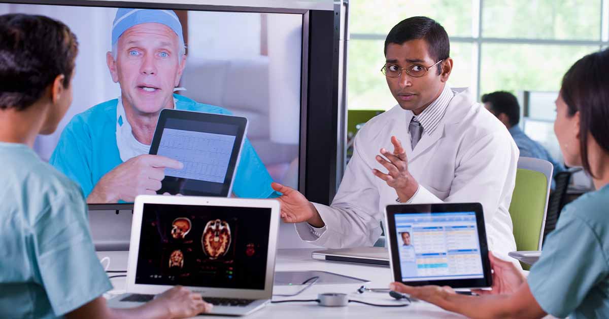 Doctors meeting with laptops and other doctor on a screen
