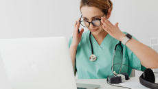 Doctor in scrubs looking at laptop