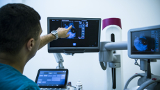 doctor points at an image on one screen at a multi-screen medical station