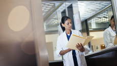 A doctor reading a paper health record from a folder