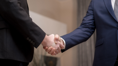 Close-up on handshake of two people in suits.