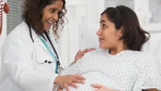 Female doctor touches a pregnant patient's belly 
