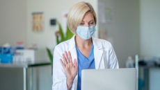A clinician waving at a patient via video chat