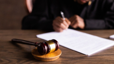 A gavel with a judge signing papers in the background