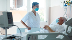 A patient in bed looking at a caregiver