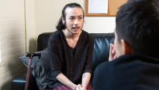 A person with a cane speaking to a healthcare provider