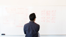 Developer faces a whiteboard looking at a tech stack diagram
