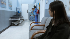 Adult sits as child is wheeled out of a medical test.