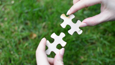 Hands fit two puzzle pieces together