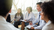 Smiling health system colleagues sit together and talk