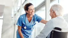 A nurse smiling at an older patient in a wheelchair