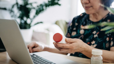 A senior patient holds up a medicine during a teleconsultation with their doctor