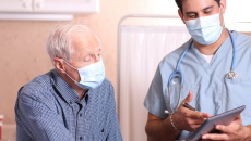 A doctor discussing with a senior patient their test results using a digital tablet