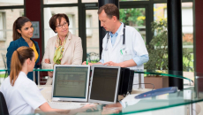 A group of clinicians conversing in a nurses' station