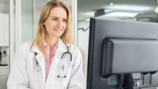 A doctor checking on a patient's file in a desktop computer
