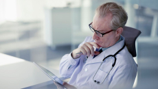 A doctor reading a patient's medical record on a digital tablet