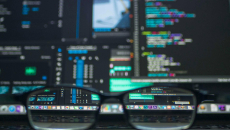 Glasses in front of computer screens with software code 