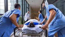 Healthcare workers rushing a patient in a gurney to the emergency room