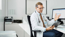 Doctor at desk talking to tablet
