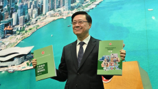 Hong Kong Chief Executive John Lee Ka-chiu holding copies of the 2025 Policy Address