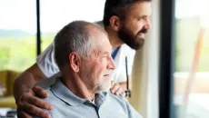 Medicare patient and caregiver look out a window and smile