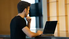 Health IT developer works on his laptop at a table