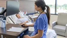 Nurse reviews patient information at the hospital bedside