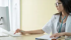 Female doctors sits at her desk and chooses a scribe application in her EHR