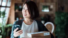 Person holding smartphone and packages