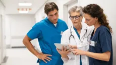 Doctor and healthcare workers in scrubs looking at tablet