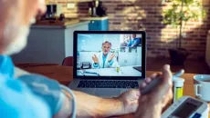 Cardiology patient checks his blood pressure during a telehealth call with his doctor