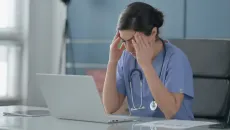 Doctor is frustrated while handling clinical documentation on her laptop 