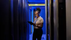 Woman reviews information on a laptop in a server room