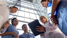 Healthcare team gathers to look at data on a tablet