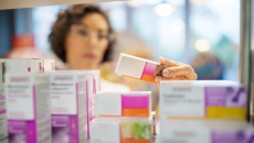 A pharmacist checking medicines on a rack