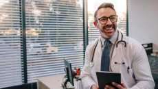 A smiling doctor at a clinic holding a digital tablet