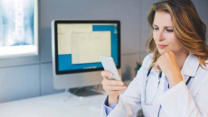 doctor at her office sitting at the table and using smart phone
